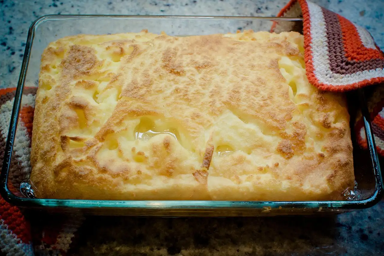 Glass casserole dish and ceramic baking dish on a kitchen counter with cooked food nearby.
