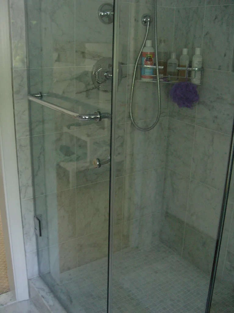 Close-up of shower door hardware being installed on a tiled wall