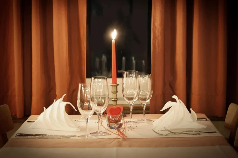 A Valentine’s Day dinner table with plated steak, candles, wine, and a receipt nearby.