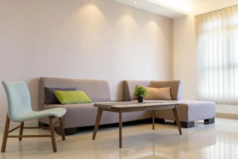 Professional cleaner assessing a three-seat fabric sofa with tools and fabric swatches in a bright living room.