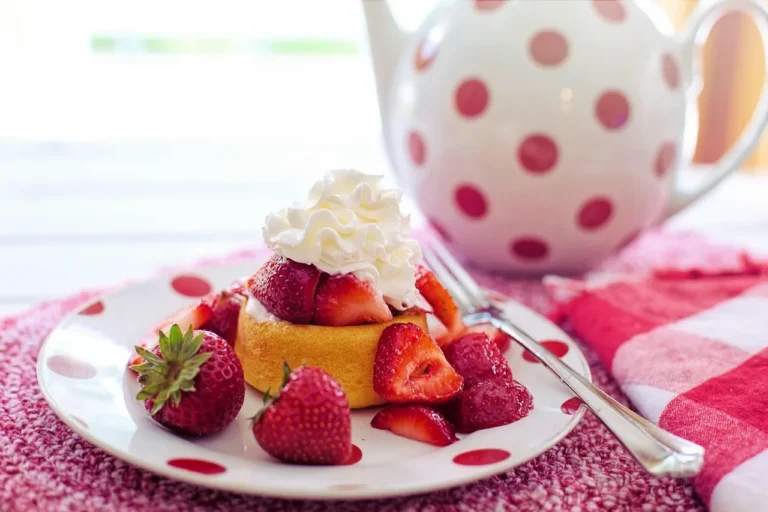 Strawberry shortcake ingredients laid out on a bright kitchen counter with fresh berries, flour, sugar, butter, cream, and eg