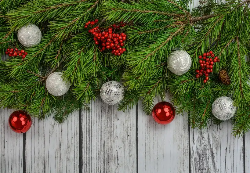 Christmas garland wrapped around a curved wooden staircase banister in natural light