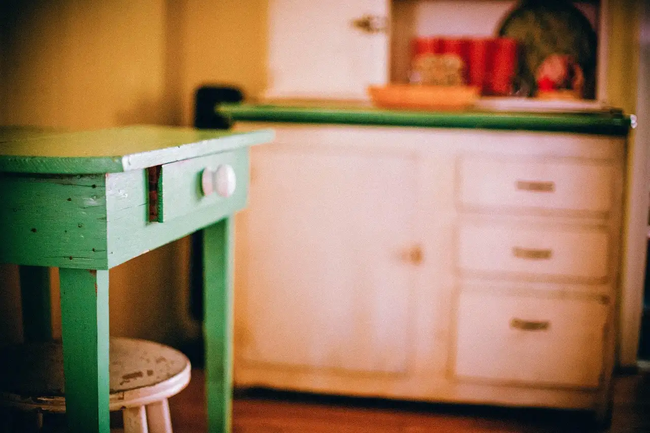 A painted wooden drawer sticking slightly in its cabinet opening on a sunlit workbench