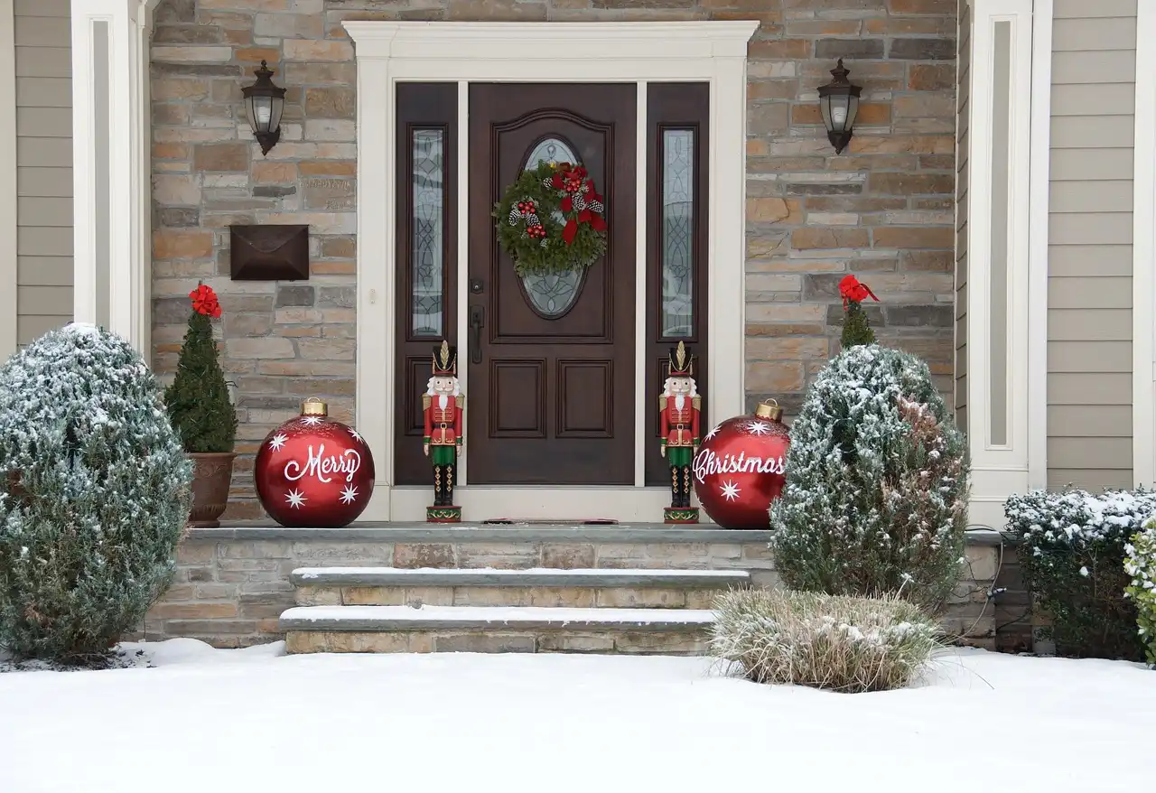 A person hangs garland on a front door with removable hooks in a bright entryway.