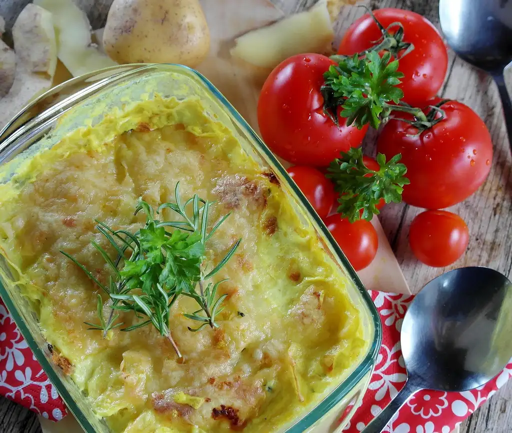 A hot casserole in a covered dish being packed into an insulated carrier on a kitchen counter