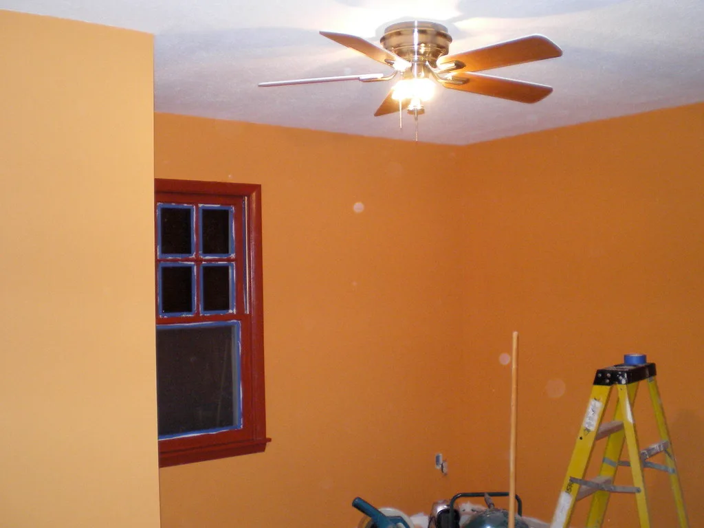 Close-up of ceiling fan installation showing bracket, wiring, and a hand with screwdriver