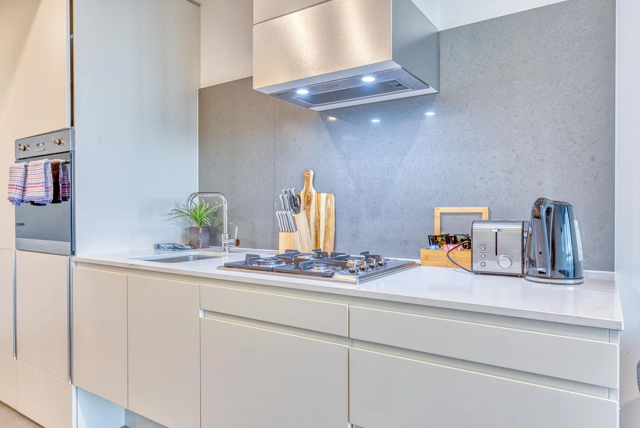 Side-by-side kitchen cabinets showing a budget laminate run and a sturdier painted shaker run in natural light