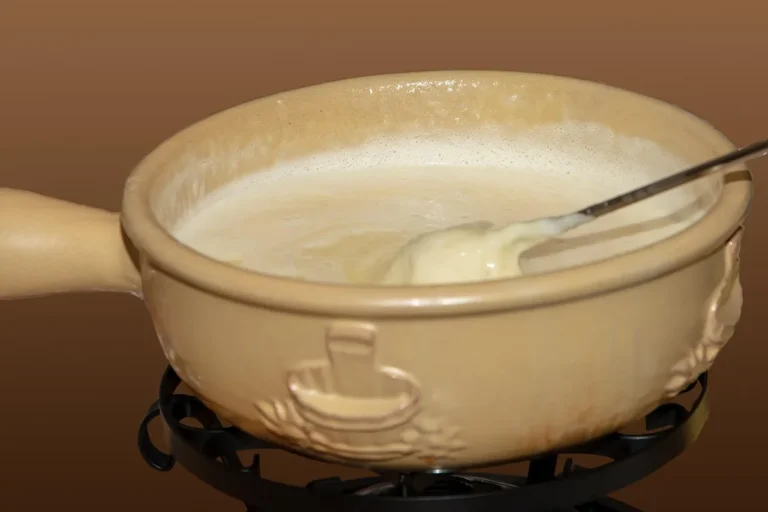 Mini fondue pot for two with melted chocolate, strawberries, and two forks on a table