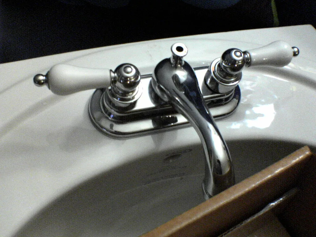 Close-up of a Moen bathroom faucet handle and aerator with maintenance tools nearby