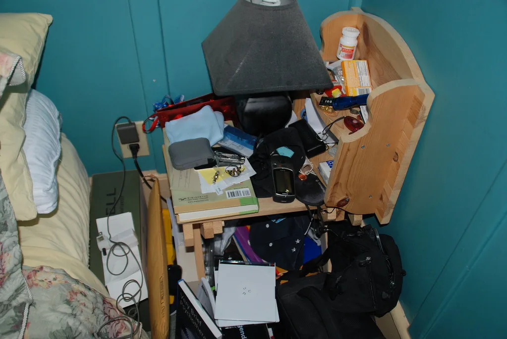 Hand measuring clearance beside a bed and small drawer table in natural light