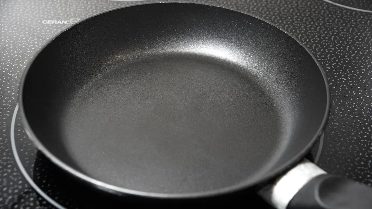 Ninja Foodi NeverStick skillet on a stovetop in a real home kitchen with dinner cooking