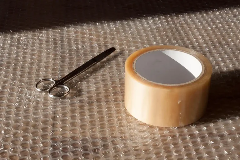 Home decor packing supplies beside two USPS-style box options on a wooden table