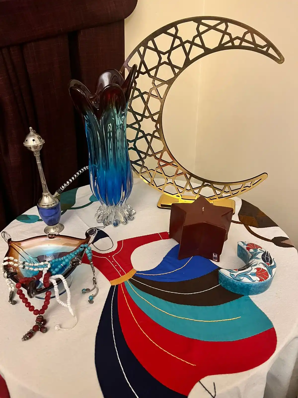 Hands arranging Ramadan table decor with a candle holder, date bowl, and linen napkin