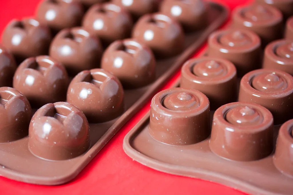 Close-up of a silicone chocolate mold being filled with melted chocolate for Valentine’s treats