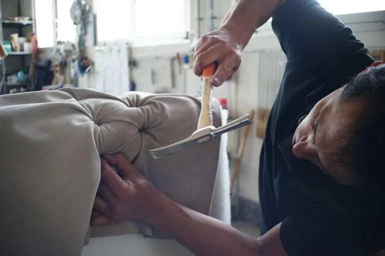 A homeowner checks a sofa with cleaning tools and repair supplies on a living room table.