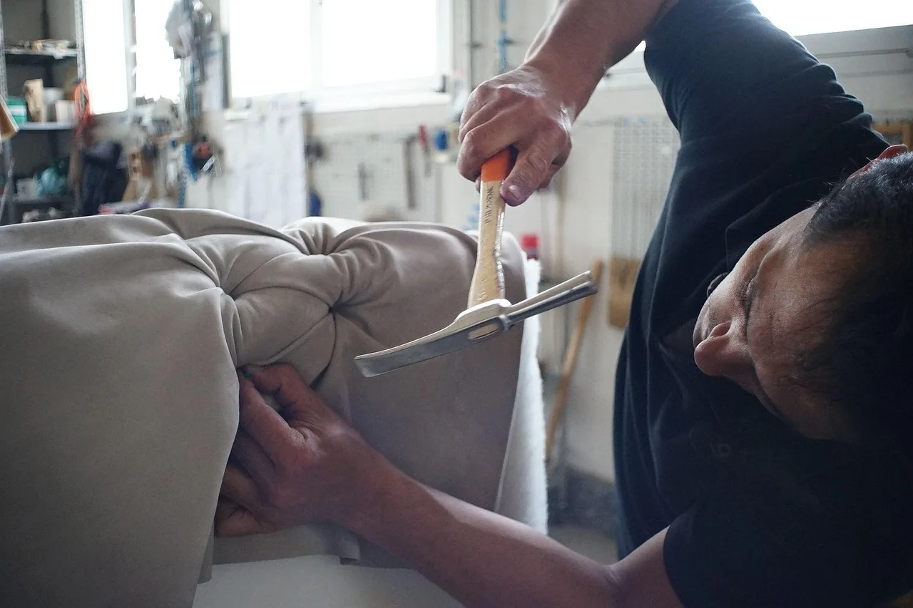A homeowner checks a sofa with cleaning tools and repair supplies on a living room table.