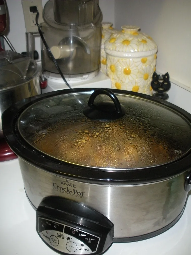 Close-up of a stainless steel roasting pan rim and riveted handles being lifted by hand