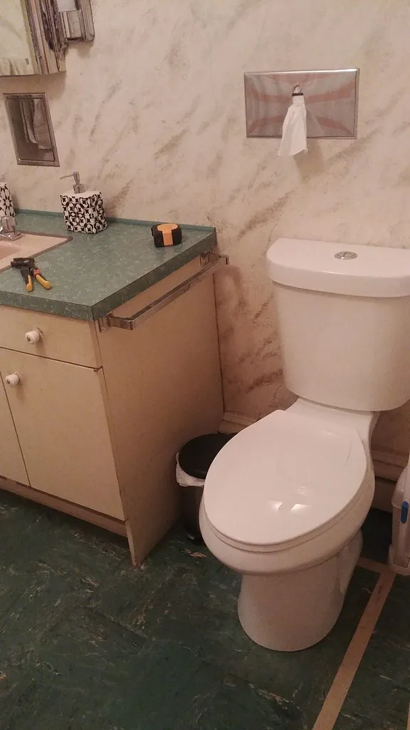 Hands placing a wax ring on a toilet flange during a bathroom replacement