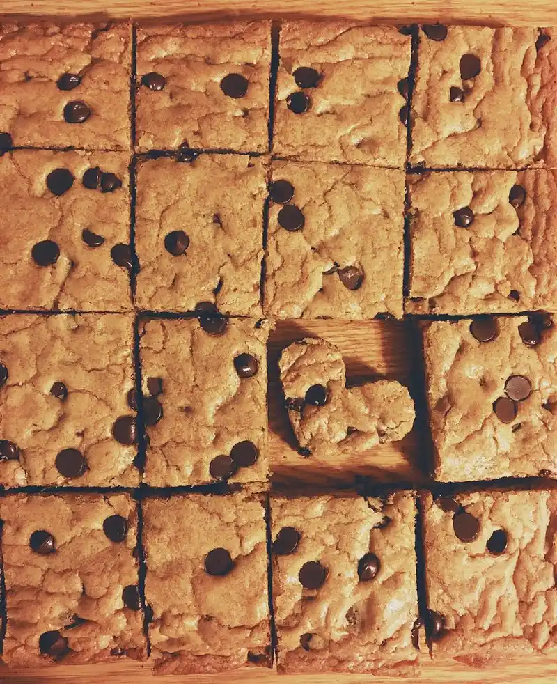 Hand pressing a heart-shaped Valentine’s Day cookie cutter into rolled cookie dough on parchment paper
