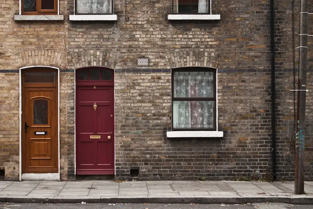 A homeowner listens beside a creaking door in a cold hallway at night.