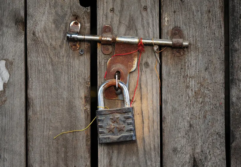 Homeowner testing a front door that won't latch in cold weather near a snowy entryway